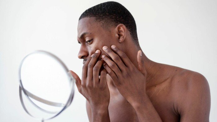 A picture of a man looking at his face through the mirror