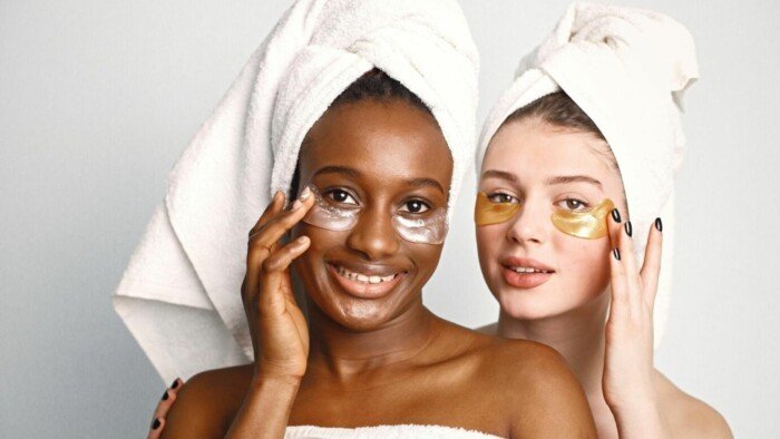 A picture of two young teenage girls with eye patches on faces have a hair wrapped in towels
